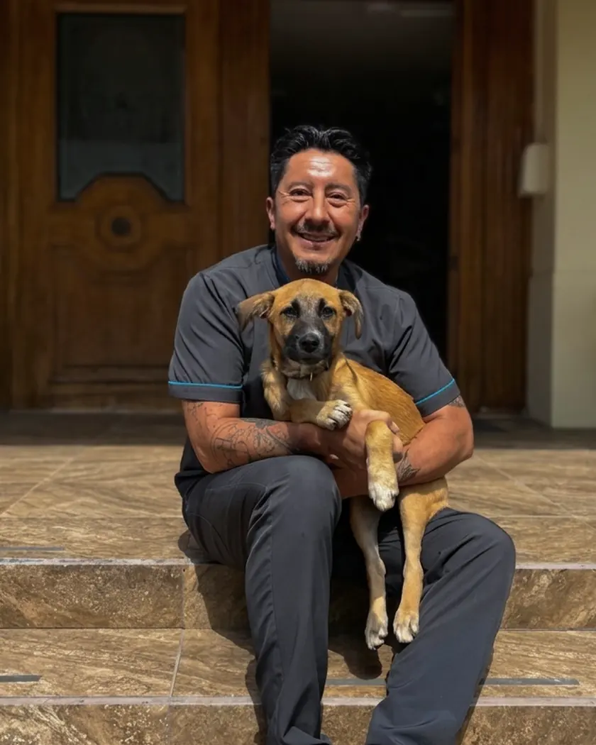 Alfredo Salgado, fundador de Terranova, sentado en las gradas de la clínica con un cachorro en brazos.